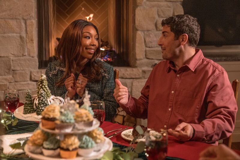 Brandy Norwood and Jason Biggs sit next to each other at a dinner table in a still from ‘Best Christmas Ever’