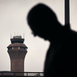 NEWARK, NEW JERSEY - MAY 6:  A man stands outside Terminal C with the airport control tower in the background at Newark Liberty International Airport, on May 6, 2025 in Newark, New Jersey. Passengers traveling to, from, or through Newark Liberty International Airport (EWR) have experienced several days of delays and cancellations caused by air traffic control staffing shortages and equipment malfunctions.(Photo by Andres Kudacki/Getty Images)