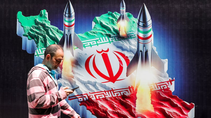 A photo including a man walking past a banner depicting missiles 