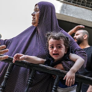 A baby cries as people leave their houses due to the Israeli airstrikes that has been going on for five days at the Sheikh Ridvan neighbourhood of Gaza City