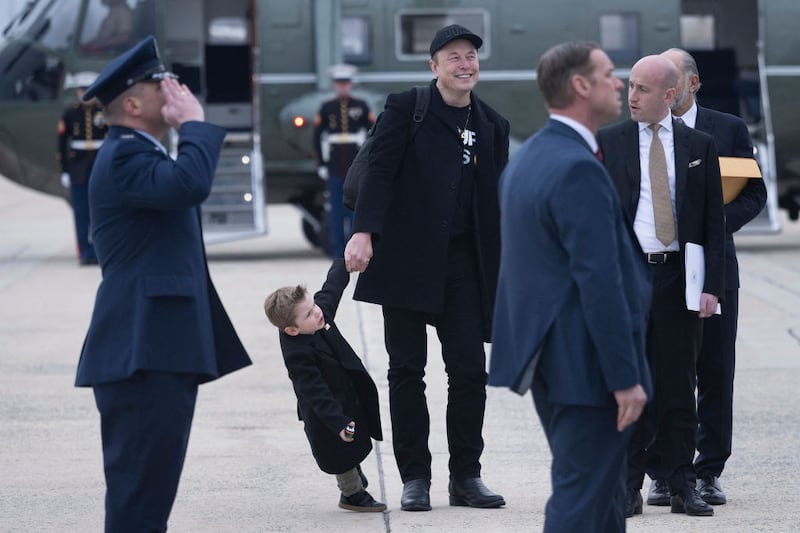Elon Musk and his son X Æ A-12 wait to follow US President Donald Trump and board Air Force One at Andrews Air Force Base March 14, 2025, in Maryland.