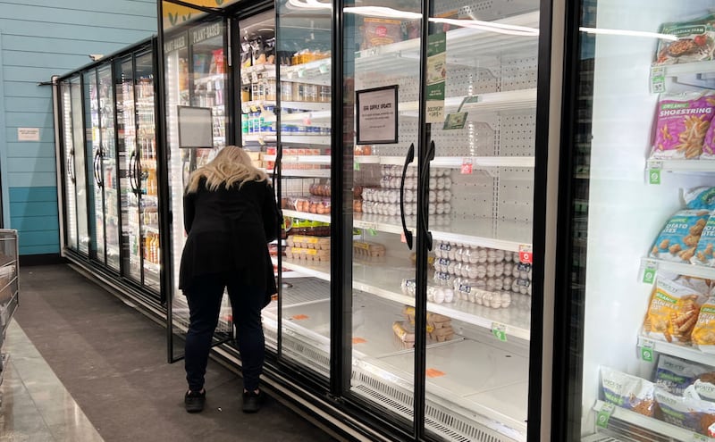 A shopper looks at the mostly empty shelves in the egg section of a grocery store in Miami, Florida.